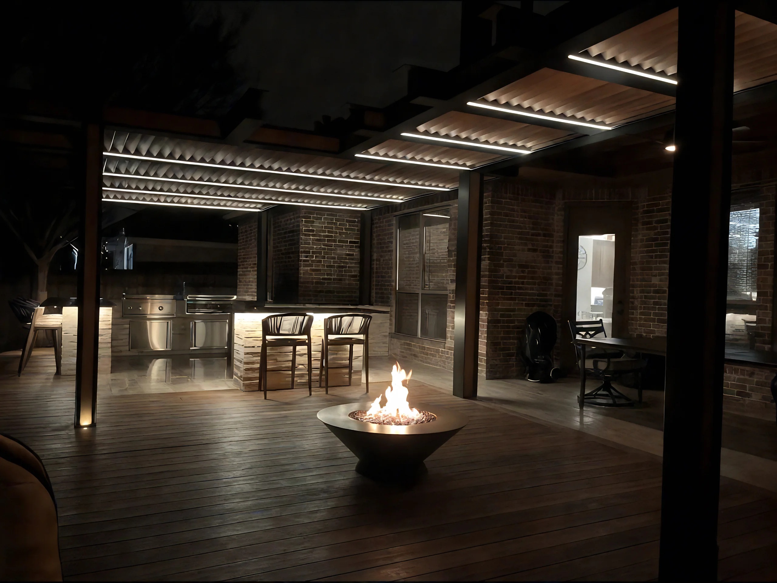 A lit fire pit in the center of a wooden deck under a modern pergola with integrated LED lighting, with a built-in outdoor kitchen with stainless steel appliances and stone countertops in the background